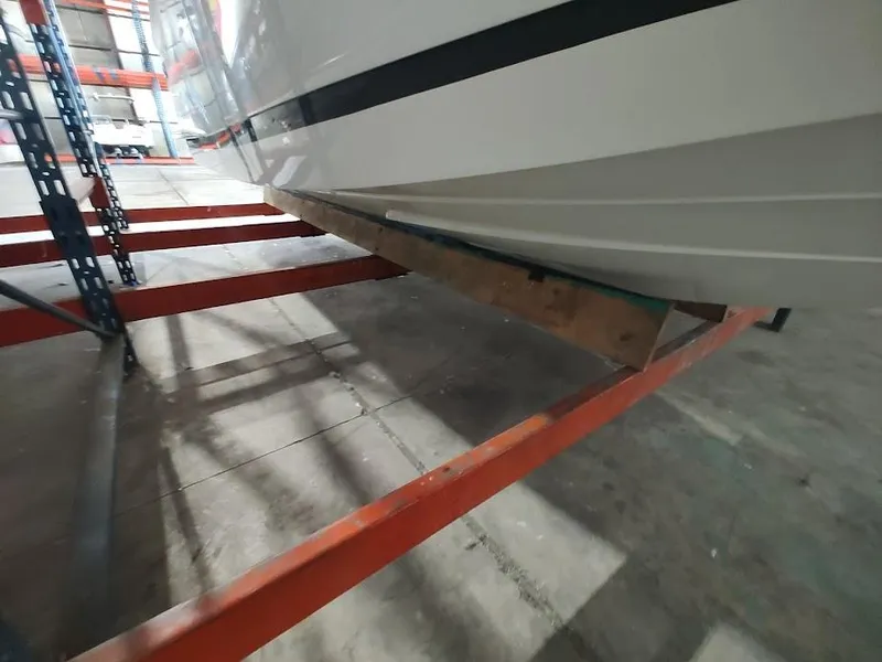 Slide: The Image of 2022 Cobalt 23SC boat hull in storage on metal racks. - 49