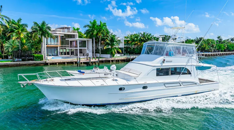 Slide: The Image of White 1996 Blackwell 72 yacht cruising near modern waterfront homes. - 11