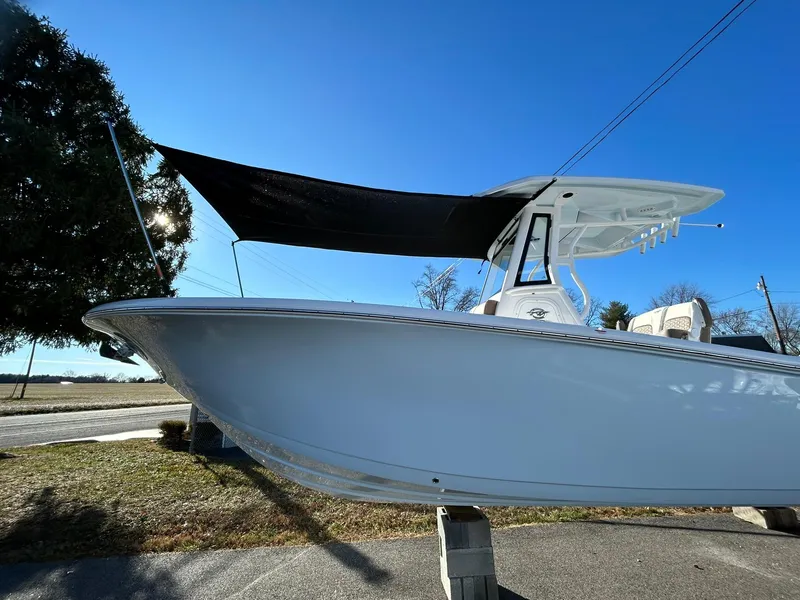 Slide: The Image of 2025 Tidewater 256 LXF boat with canopy, displayed outdoors under clear blue sky. - 2
