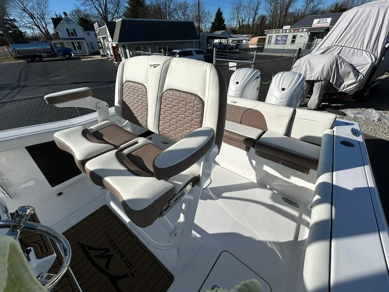 Slide: The Image of 2025 Tidewater 256 LXF boat interior with cushioned seating and dual outboard motors. - 47
