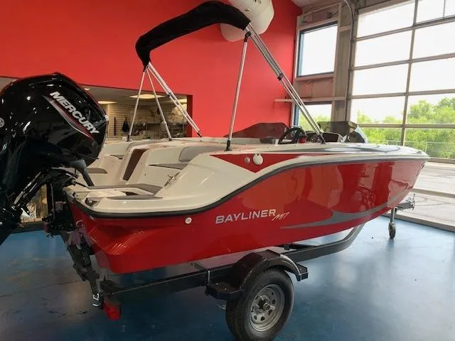 Slide: The Image of 2024 Bayliner Element M17 boat in showroom, red hull, Mercury outboard motor. - 1