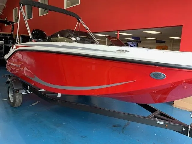Slide: The Image of 2024 Bayliner Element M17 boat in showroom, red hull, on trailer. - 2