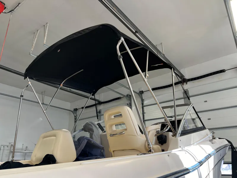 Slide: The Image of 2016 Grady-White Freedom 225 boat with black bimini top in a garage. - 34