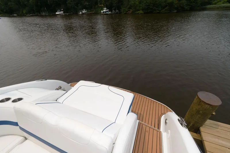 Slide: The Image of 2012 Formula 310 Bowrider boat with white seating and wooden deck by a calm lake. - 9
