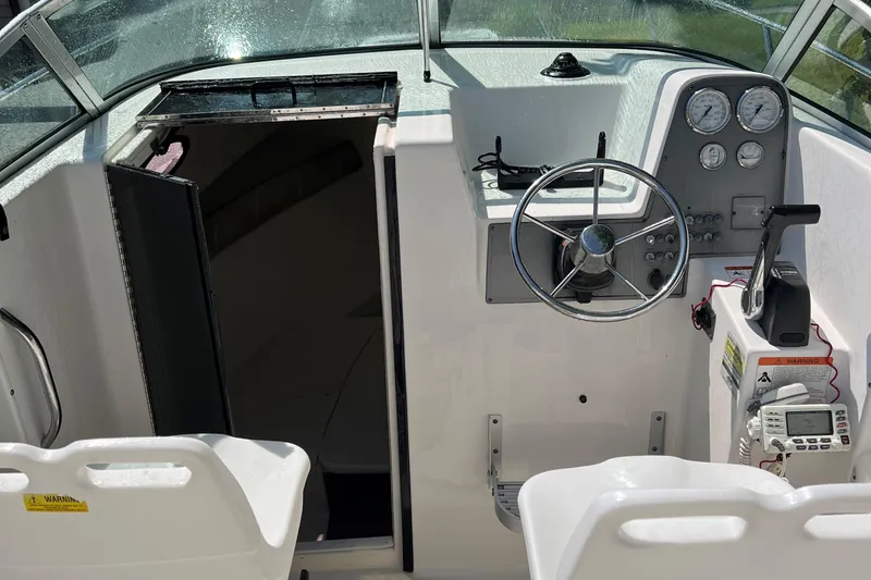 Slide: The Image of 2005 Aquasport 215 Explorer boat cockpit with steering wheel and cabin entrance. - 7