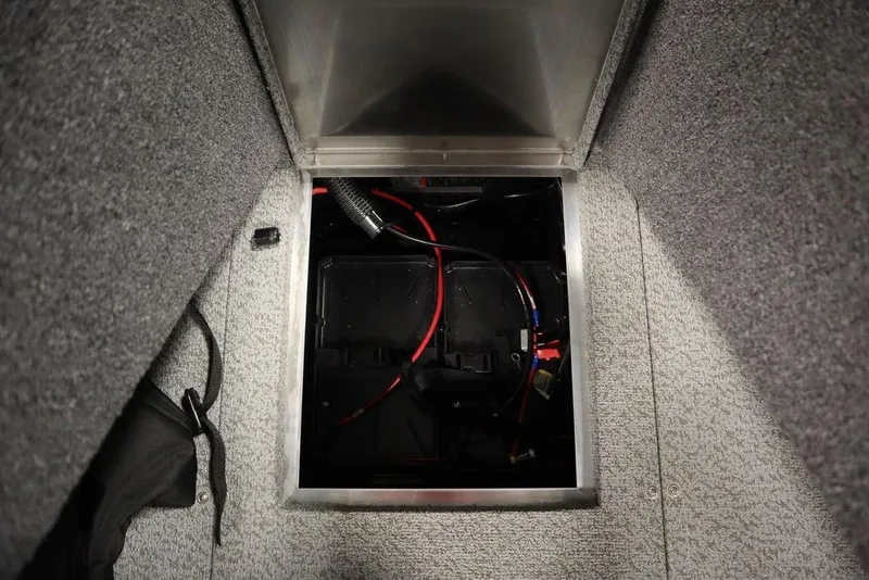 Slide: The Image of 2024 Lowe Fishing Machine 1675WT battery compartment with wiring and storage. - 26