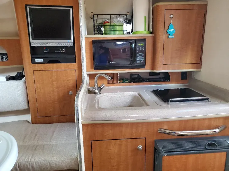 Slide: The Image of 2006 Sea Ray 280 Sundancer interior with kitchenette, microwave, sink, and TV. - 11