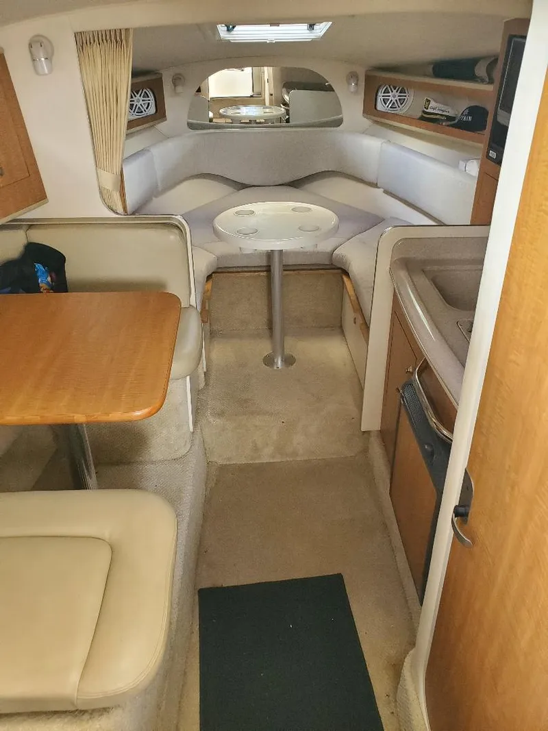 Slide: The Image of Interior of 2006 Sea Ray 280 Sundancer with seating, table, and compact kitchen area. - 13