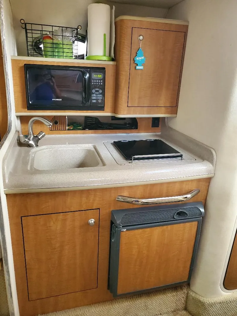 Slide: The Image of Compact kitchen in 2006 Sea Ray 280 Sundancer with microwave, sink, and storage cabinets. - 5