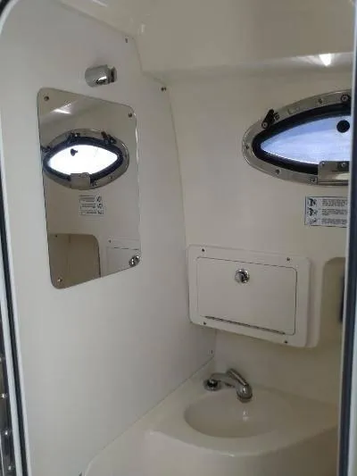 Slide: The Image of 2014 Scout 262 Abaco boat interior bathroom with sink, mirror, and porthole window. - 13