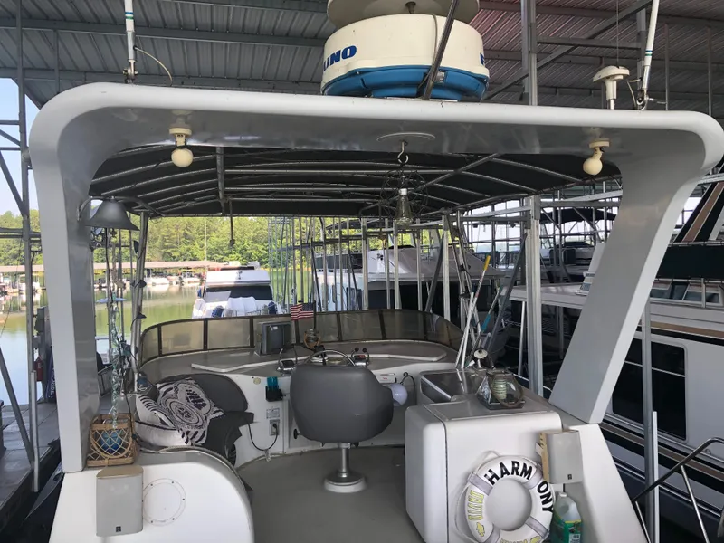 Slide: The Image of 1990 Bluewater Sedan boat docked in a marina, featuring a covered deck and seating area. - 13