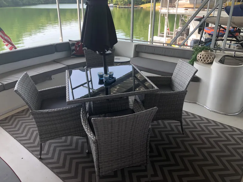 Slide: The Image of Outdoor seating area on a 1990 Bluewater Sedan boat with wicker furniture and lake view. - 15