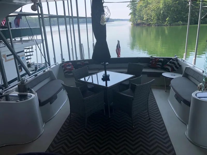 Slide: The Image of 1990 Bluewater Sedan boat with outdoor seating area on a serene lake. - 16