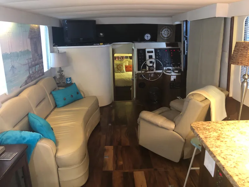 Slide: The Image of 1990 Bluewater Sedan interior with beige leather seating, wooden flooring, and helm station. - 18