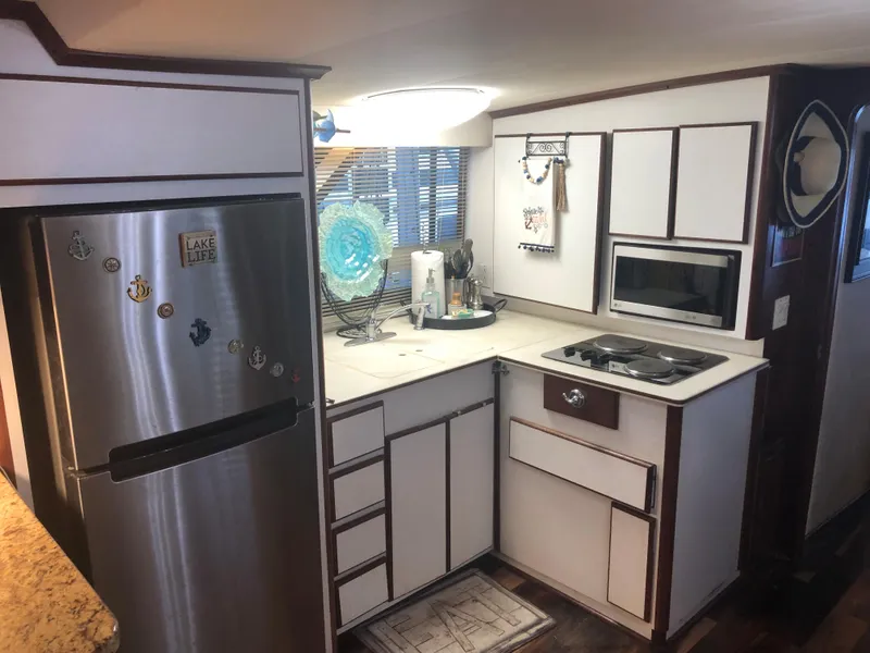 Slide: The Image of 1990 Bluewater Sedan kitchen with stainless steel fridge, stove, and white cabinets. - 22