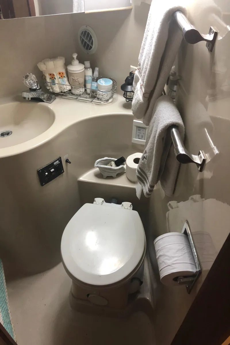 Slide: The Image of Compact bathroom in a 1990 Bluewater Sedan boat with sink, toilet, and toiletries. - 30