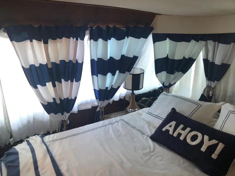 Slide: The Image of Nautical-themed bedroom in a 1990 Bluewater Sedan with striped curtains and Ahoy! pillow. - 32