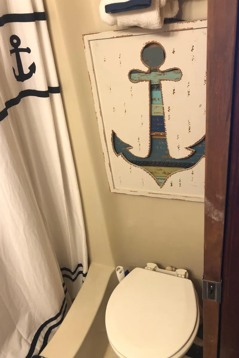 Slide: The Image of Nautical-themed bathroom in a 1990 Bluewater Sedan boat with anchor decor. - 39