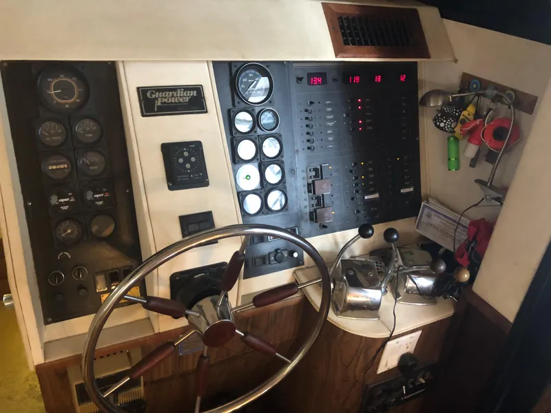 Slide: The Image of 1990 Bluewater Sedan boat control panel with steering wheel and gauges. - 48