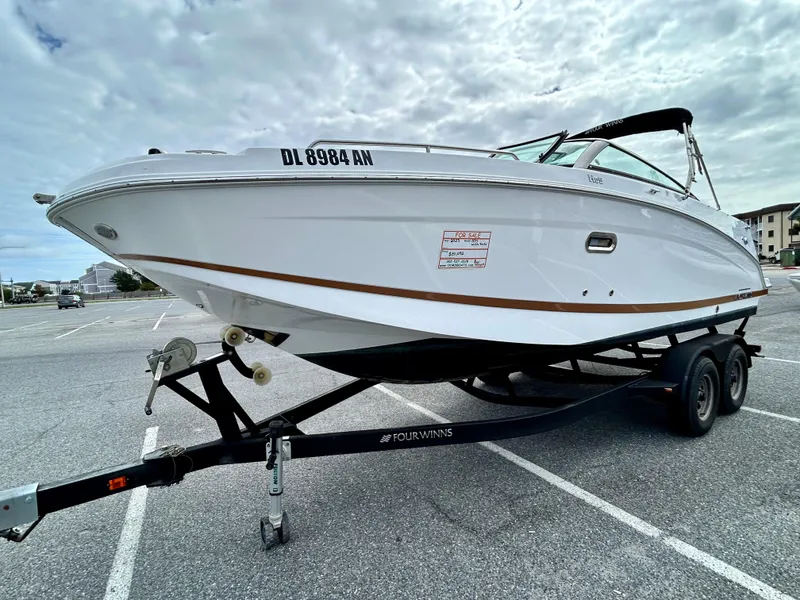 Slide: The Image of 2022 Four Winns HD5 OB boat on trailer in parking lot under cloudy sky. - 3