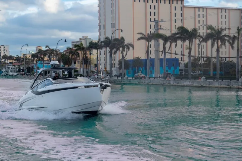 Slide: The Image of 2023 Fairline F//Line 33 Outboard cruising in a city canal with palm trees and buildings. - 8