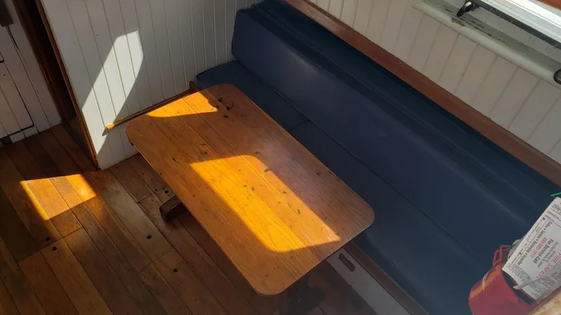 Slide: The Image of Wooden table and blue bench seating inside a 1996 Custom Biloxi Schooner. - 21