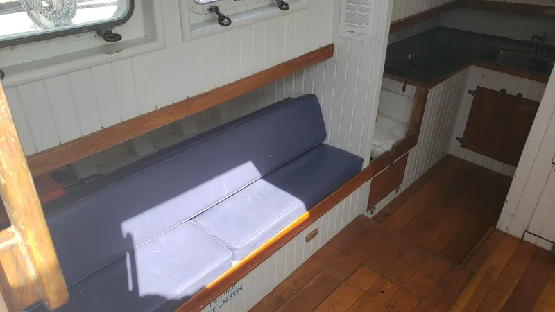 Slide: The Image of Interior of a 1996 Custom Biloxi Schooner with wooden floors and a blue cushioned bench. - 22