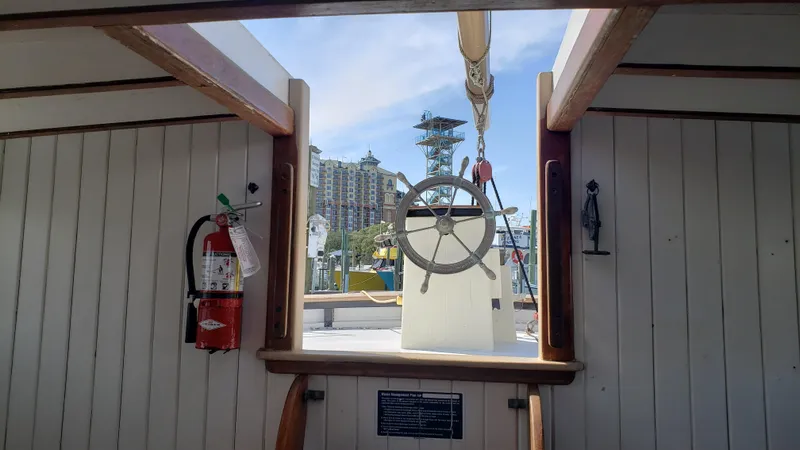 Slide: The Image of Interior view of 1996 Custom Biloxi Schooner with ship's wheel and cityscape background. - 30