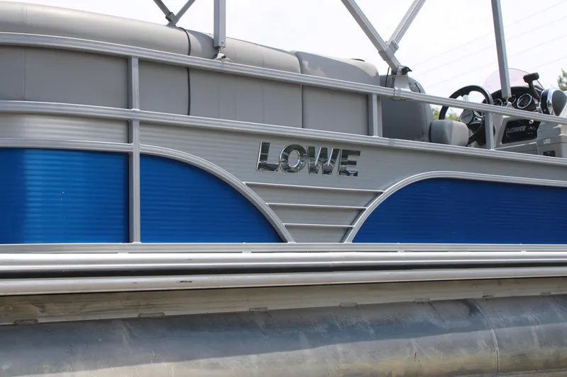 Slide: The Image of 2021 Lowe SS250 Super Sport pontoon boat side view with blue and silver design. - 4