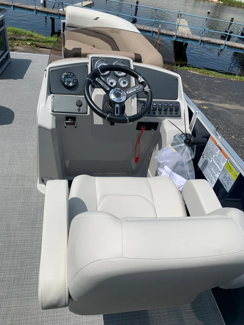 Slide: The Image of 2023 Starcraft EX 24 R boat cockpit with steering wheel and captain's chair. - 2