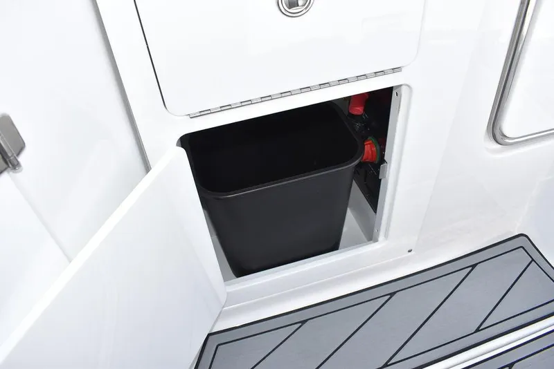 Slide: The Image of 2024 Monterey M6 boat storage compartment with a black trash bin. - 46