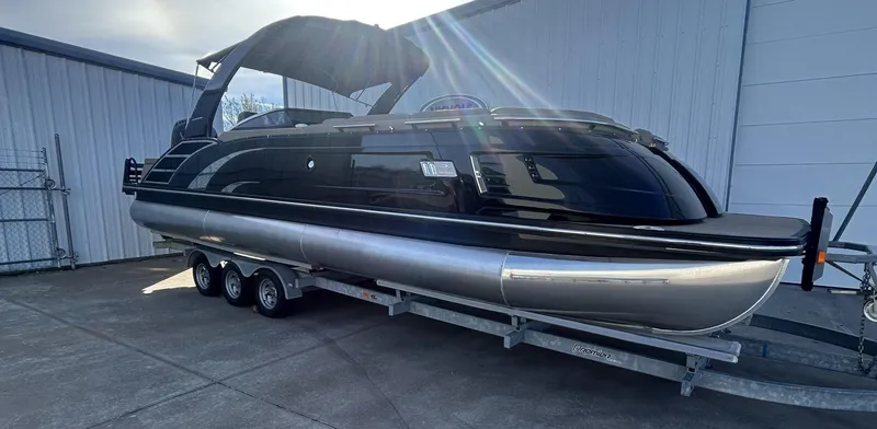 Slide: The Image of 2023 Bennington 28 QXSBW pontoon boat on trailer, parked outdoors. - 1