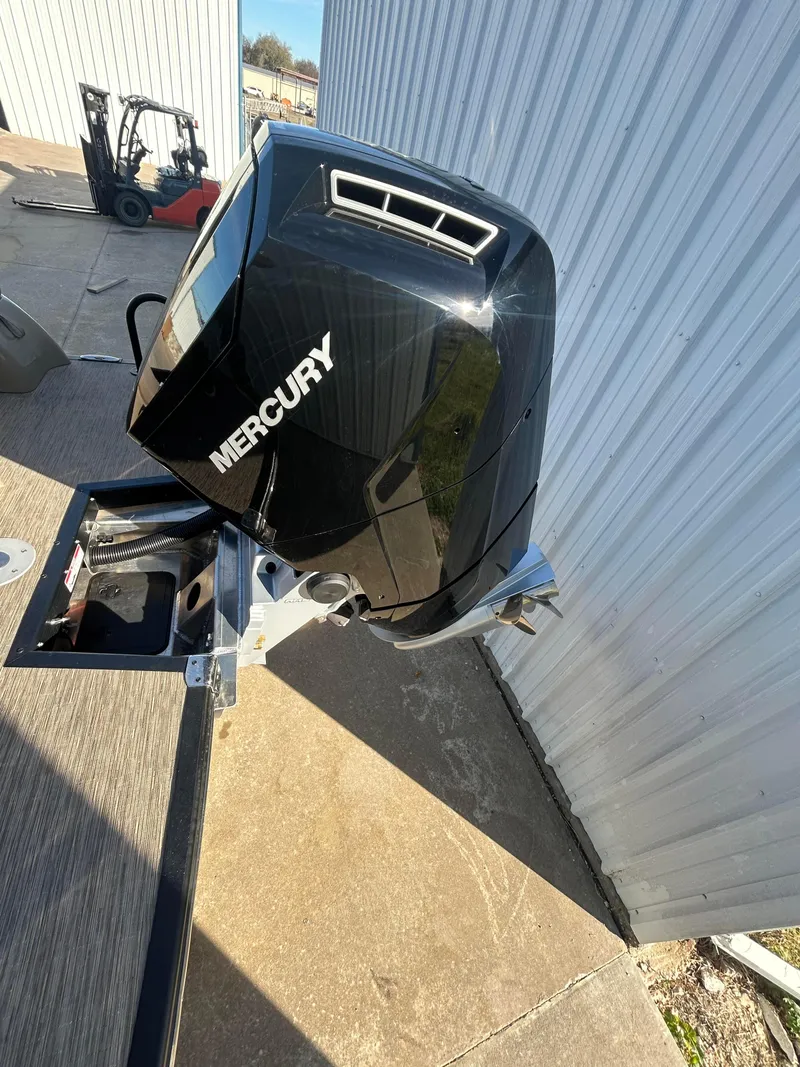 Slide: The Image of 2023 Bennington 28 QXSBW with Mercury outboard motor, docked near metal building. - 12