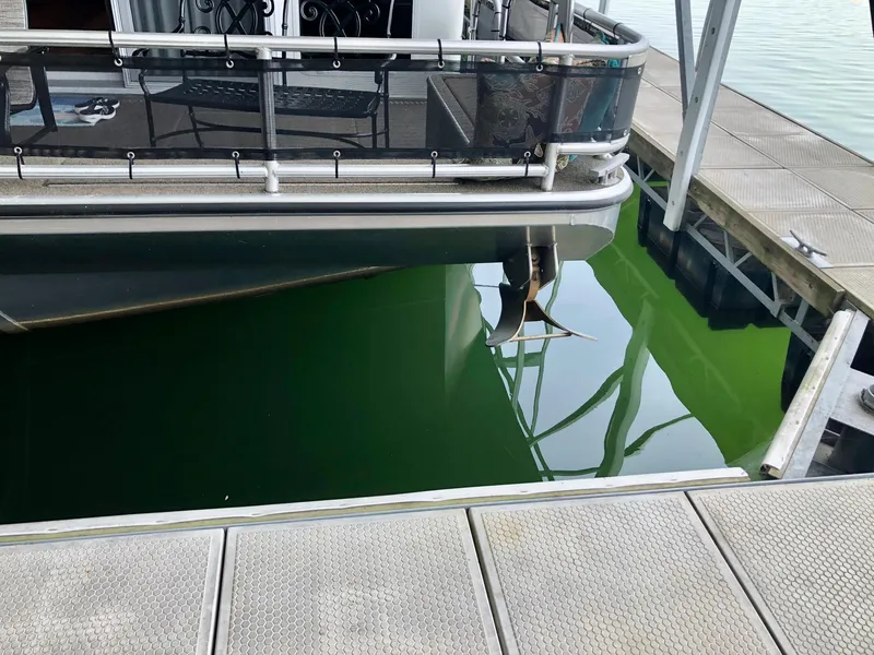 Slide: The Image of Thoroughbred 67x17 houseboat docked, propeller visible in green water, 2016 model. - 16