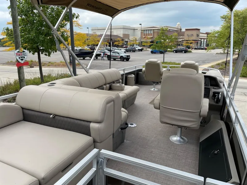 Slide: The Image of 2024 Sun Tracker Sportfish 24 XP3 pontoon boat with beige seating in a parking lot. - 4