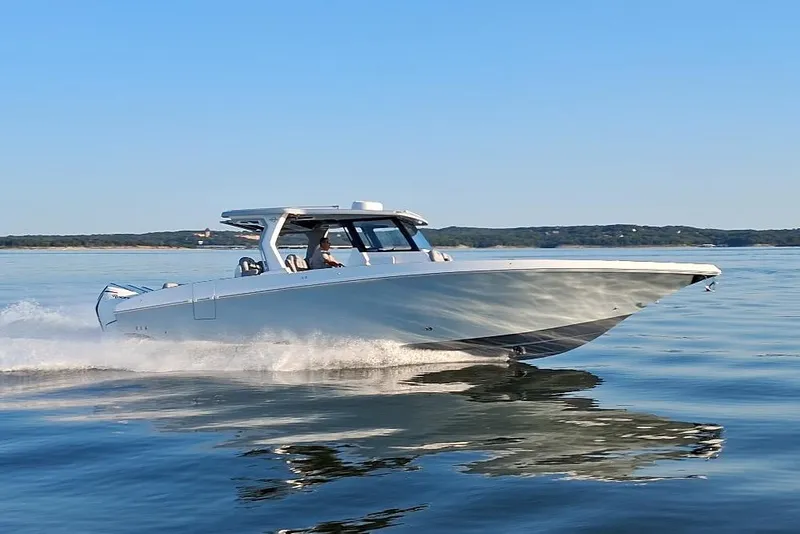 The Image of 2023 Fountain 38 SCX boat cruising on calm water under clear blue sky. - 0