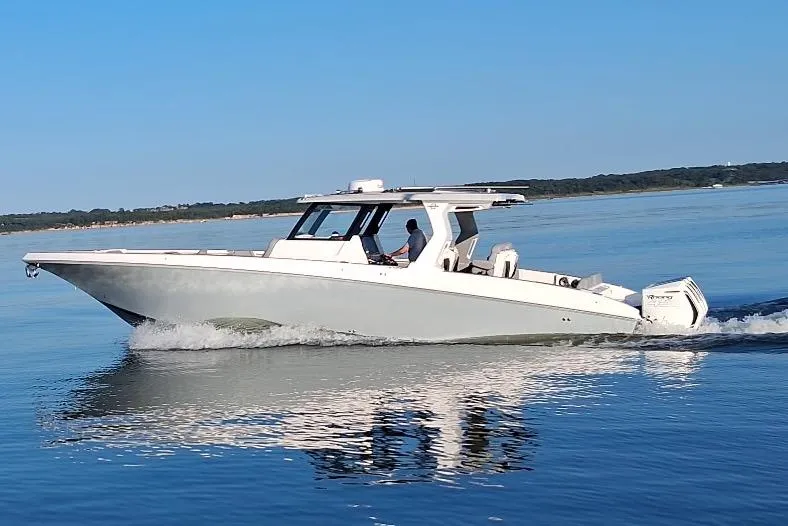 Slide: The Image of 2023 Fountain 38 SCX boat cruising on calm water under clear blue sky. - 13