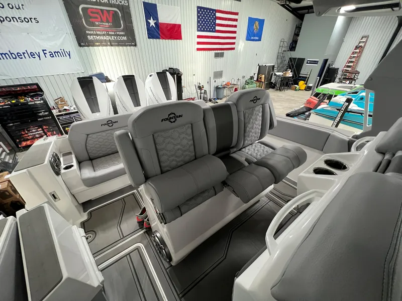 Slide: The Image of 2023 Fountain 38 SCX boat interior with gray seating and cup holders in a workshop. - 36