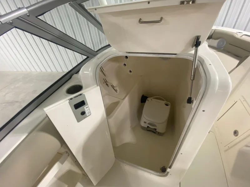 Slide: The Image of 2024 Key West 239 DFS boat interior with open storage compartment and portable toilet. - 19