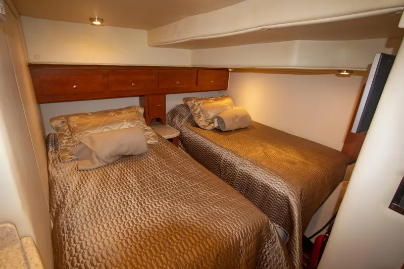 Slide: The Image of 2008 Rinker 400 Express Cruiser cabin with twin beds and wooden storage cabinets. - 13