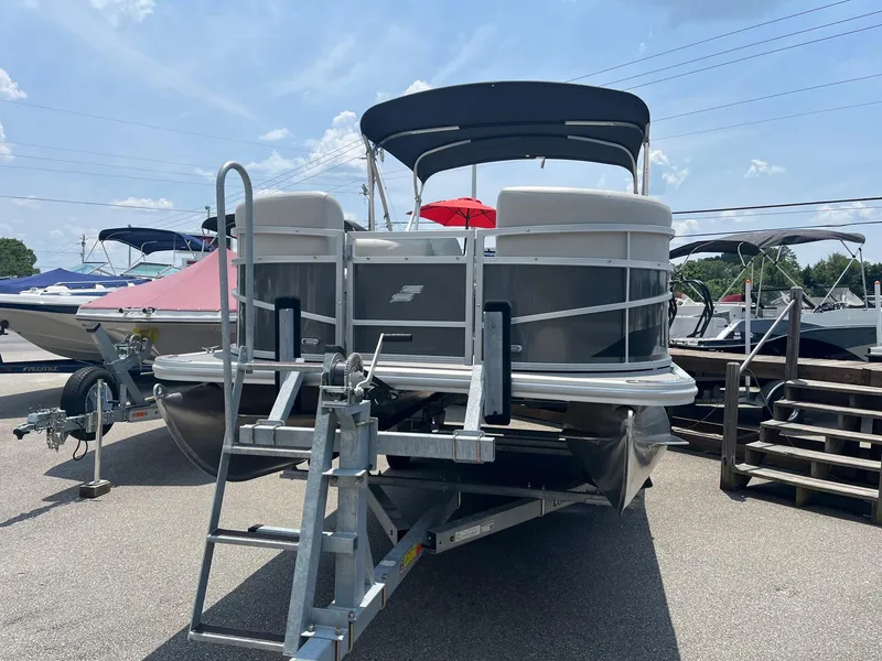 Slide: The Image of 2024 Starcraft LX22 F pontoon boat on trailer in marina. - 2