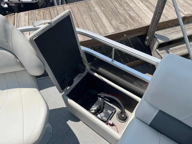 Slide: The Image of 2024 Starcraft LX22 F boat storage compartment with open lid and visible battery. - 7