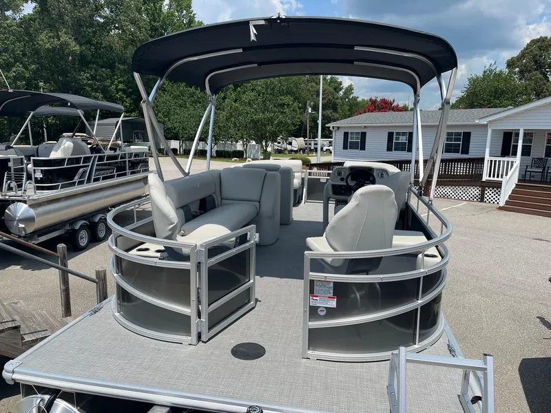 Slide: The Image of 2024 Starcraft LX22 F pontoon boat with canopy and seating, parked on a trailer. - 4