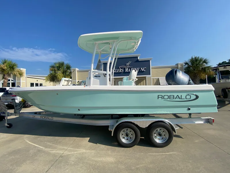 Slide: The Image of 2024 Robalo 226 Cayman boat on a trailer at a dealership. - 0