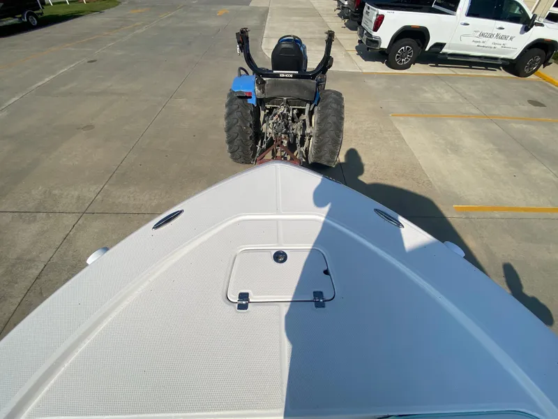 Slide: The Image of 2024 Robalo 226 Cayman boat on trailer, viewed from bow, with tractor and truck in background. - 25