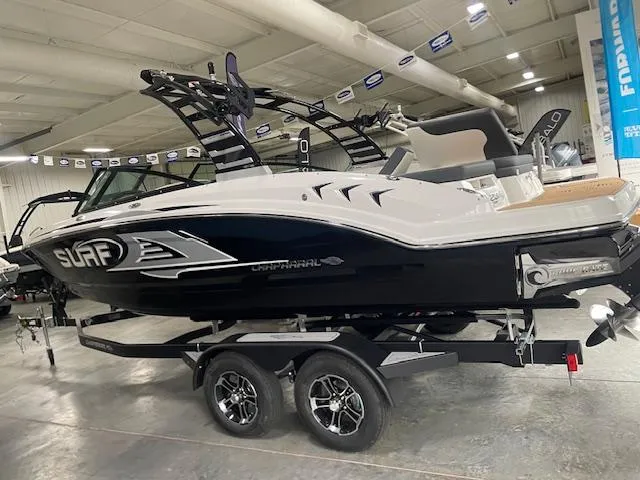 Slide: The Image of 2025 Chaparral 23 Surf boat in showroom, black and white design, on trailer. - 1
