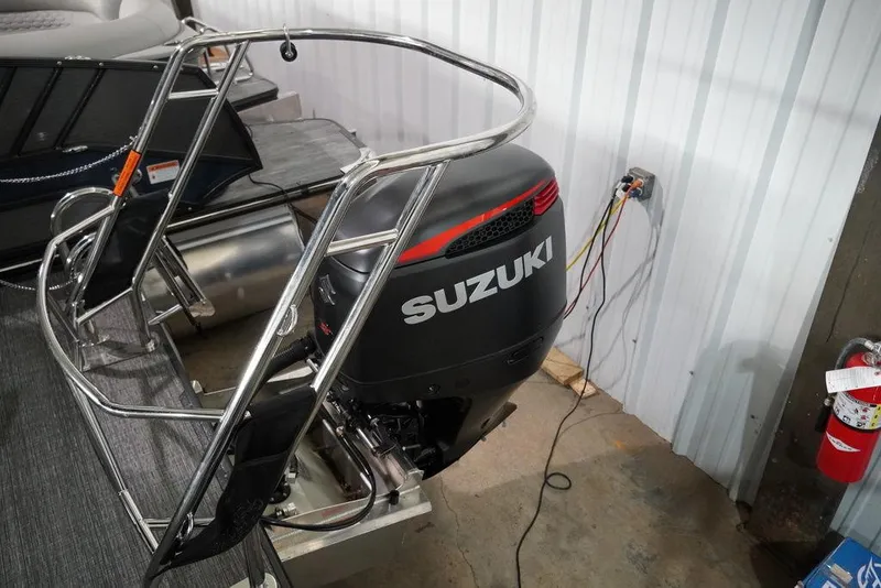 Slide: The Image of 2024 Crest Classic Platinum 240 SLRC with Suzuki outboard motor in a storage area. - 15