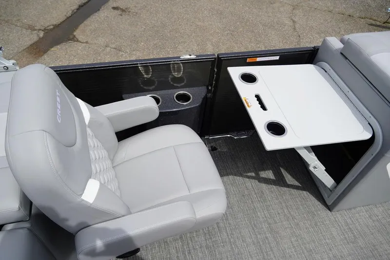 Slide: The Image of 2024 Crest Classic DLX 220 SLRC boat interior with gray seating and fold-out table. - 10