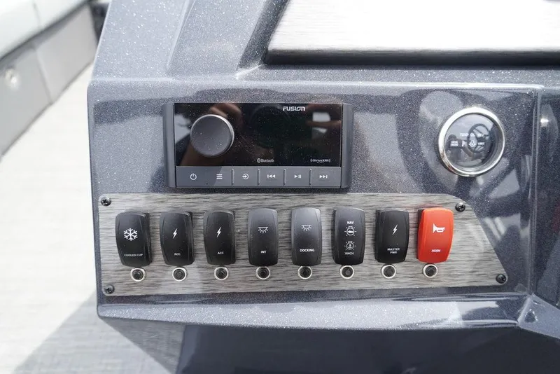 Slide: The Image of Control panel of the 2024 Crest Classic DLX 220 SLRC boat with various switches and a Fusion audio system. - 9