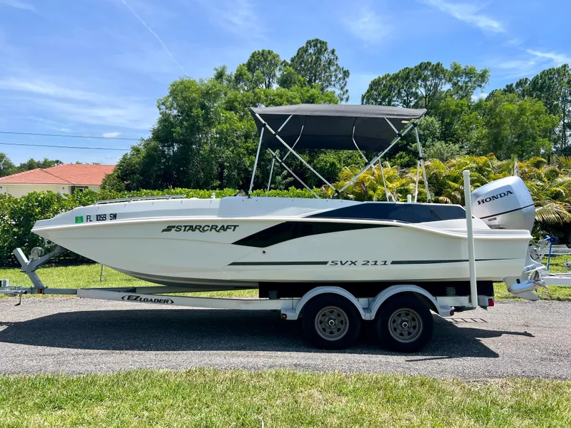 Slide: The Image of 2021 Starcraft 211 SVX boat on a trailer with a Honda outboard motor. - 0